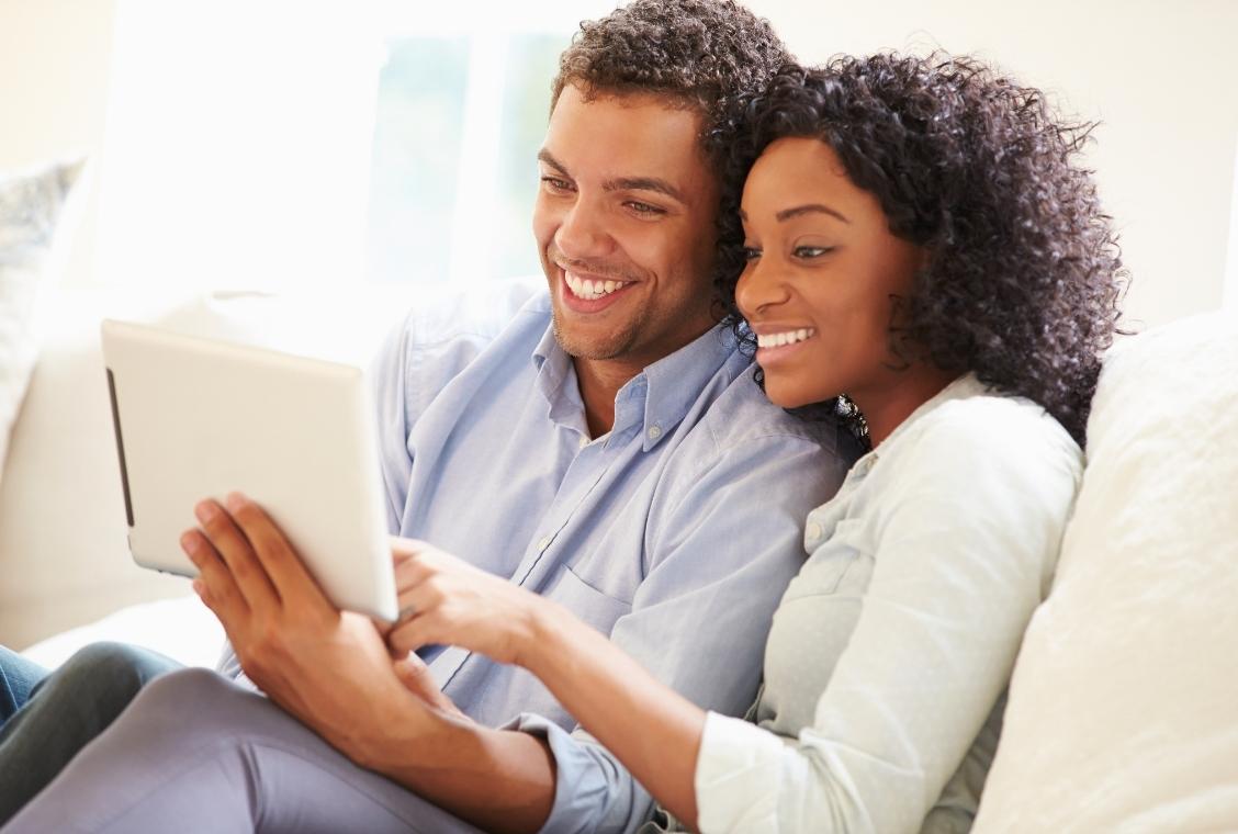 young couple on couch looking at iPad together