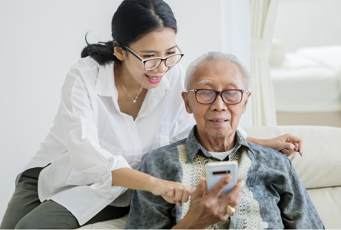 Elderly man using a phone with his daughter.