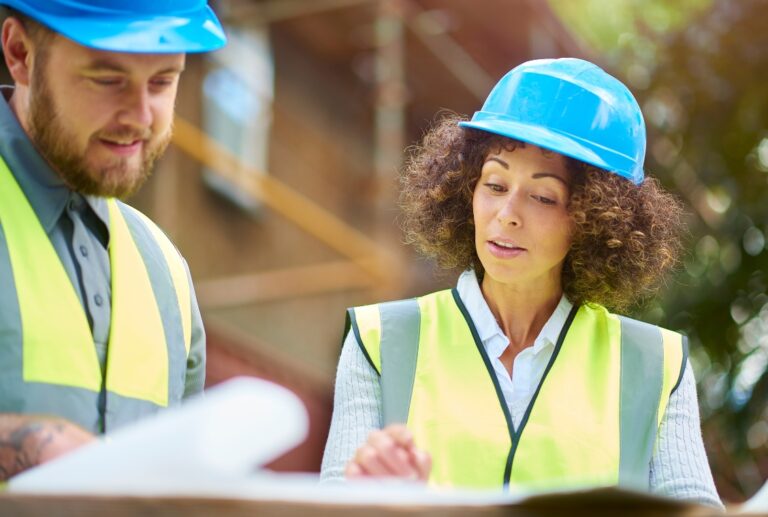 Two contractors on a construction site looking over building plans
