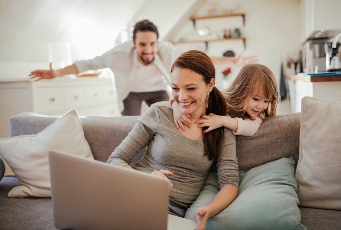 Family sitting on couch looking at computer.